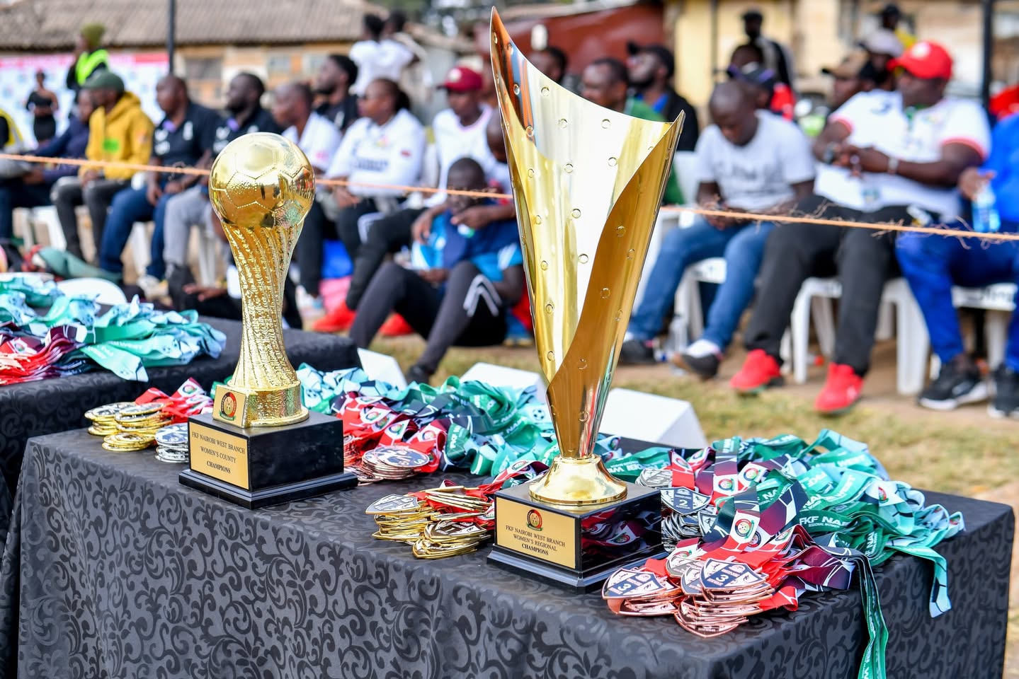 The Nairobi West women's county and regional champions trophies on a table beside stacks of medals